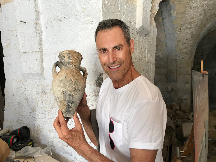 Uri Geller holds a water or oil jug that was discovered during the work in the museum.